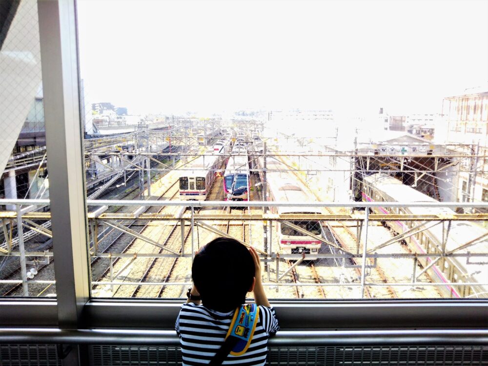 京王線の高幡不動駅にある車両基地｜京王線側・電車を眺める子供