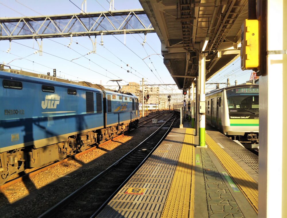 ＪＲ八王子駅の横浜線の橋本・桜木町方面・先頭車両側ホームと電車、隣の線路には貨物列車ブルサンダーが停車