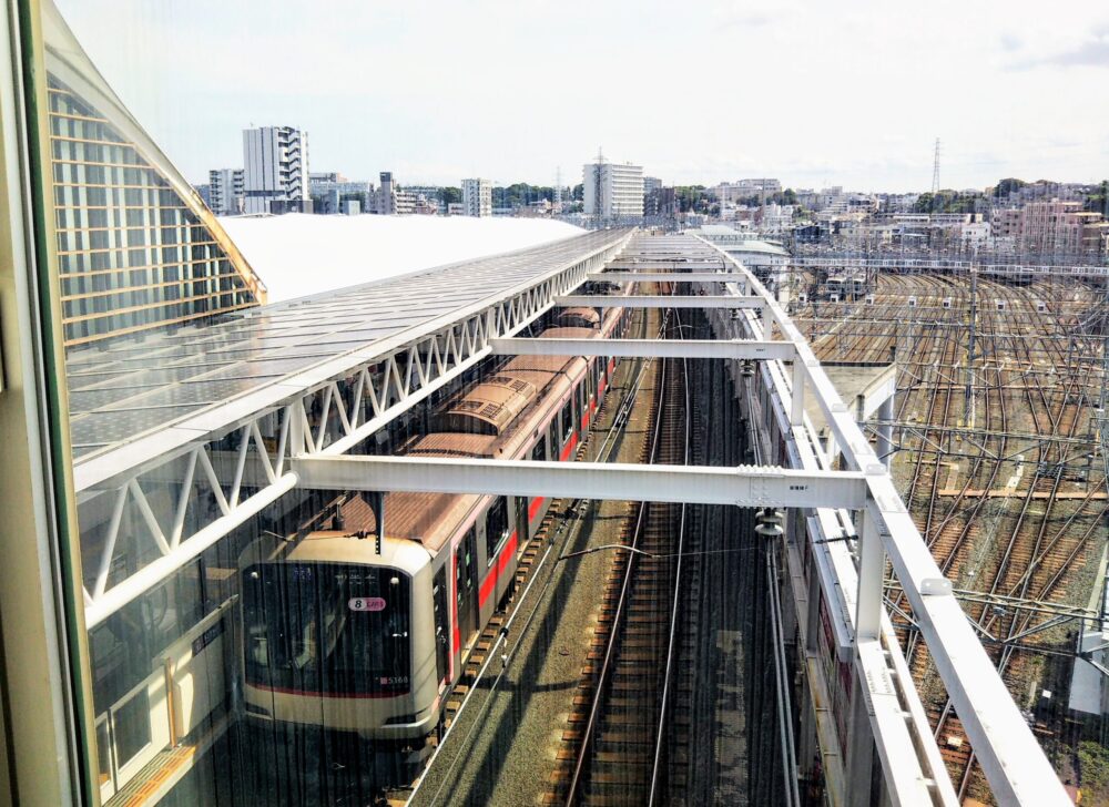 東急線の元住吉駅の改札フロアで見える車両基地とホームに停車する電車