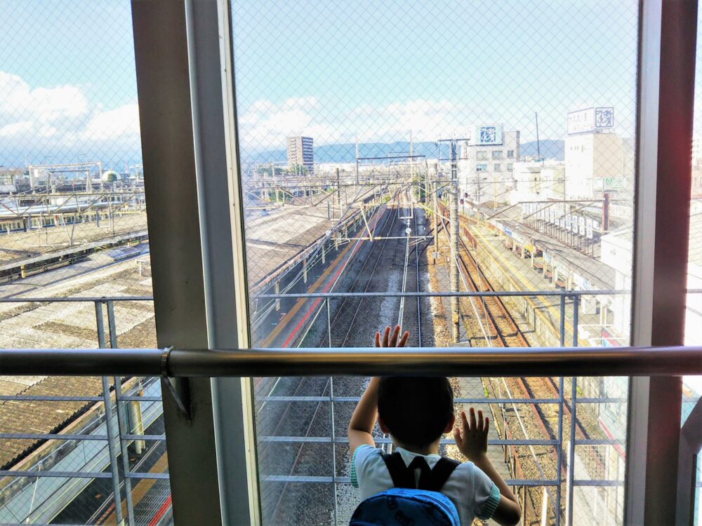 小田原駅構内で見える大雄山線と東海道線のホームと電車を見下ろす子供