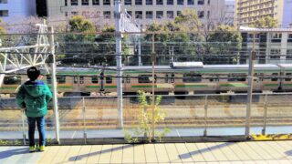 カワサキデルタ｜線路沿いデッキから見える東海道本線の電車と電車を眺める子供