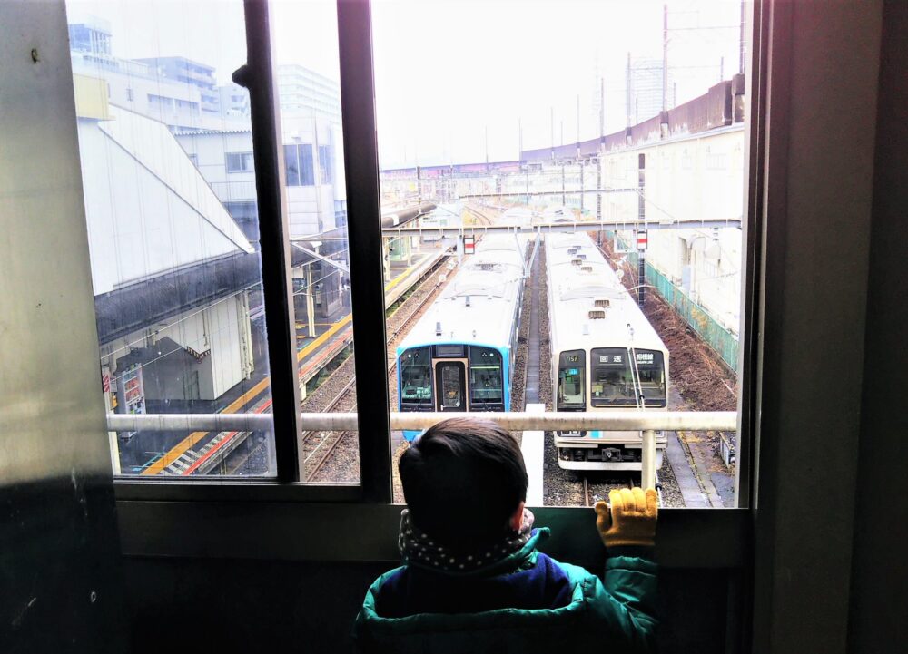 橋本駅構内から見える相模線の車両と眺める子供