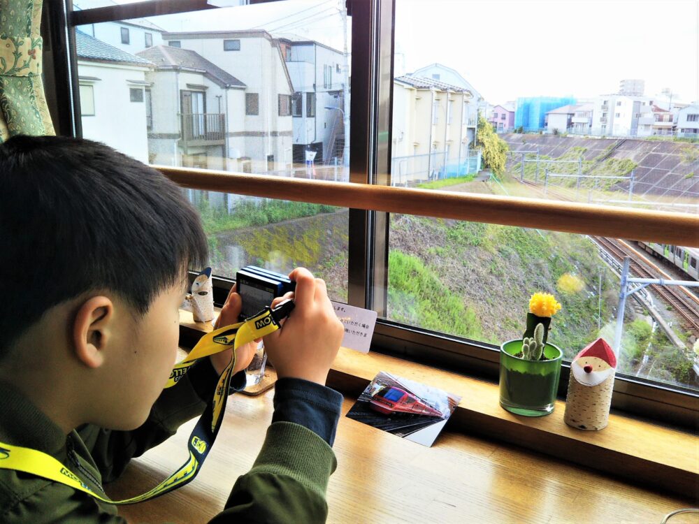 電車が見えるカフェ「カフェ-ノースライト」｜カウンター席で写真撮影する子供