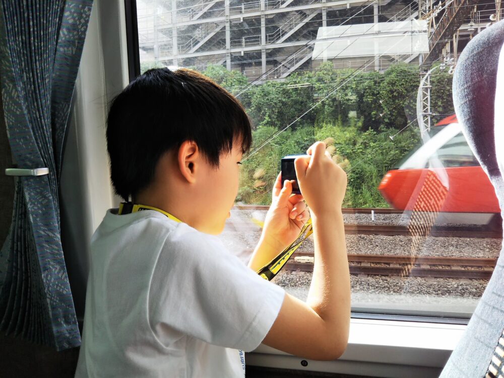 ロマンスカーEXEα｜先頭車両１０号車の最前列１４A・車体側面側の窓から撮影する子供